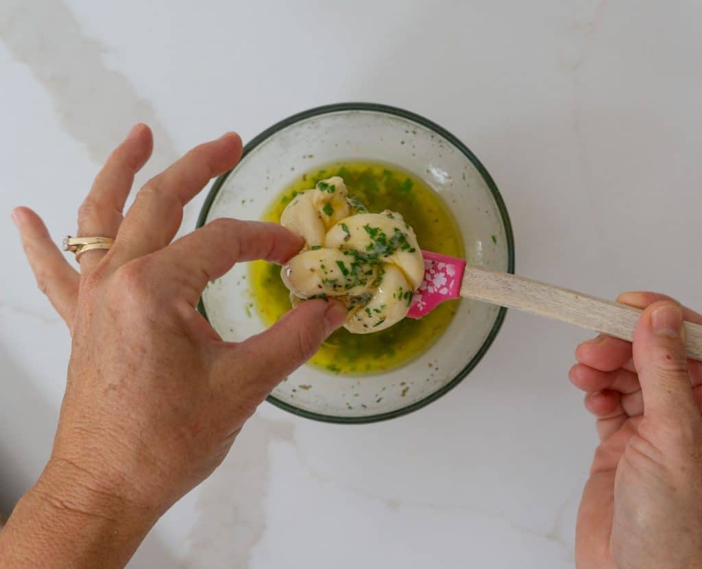 dipping garlic knot into butter herb mixture