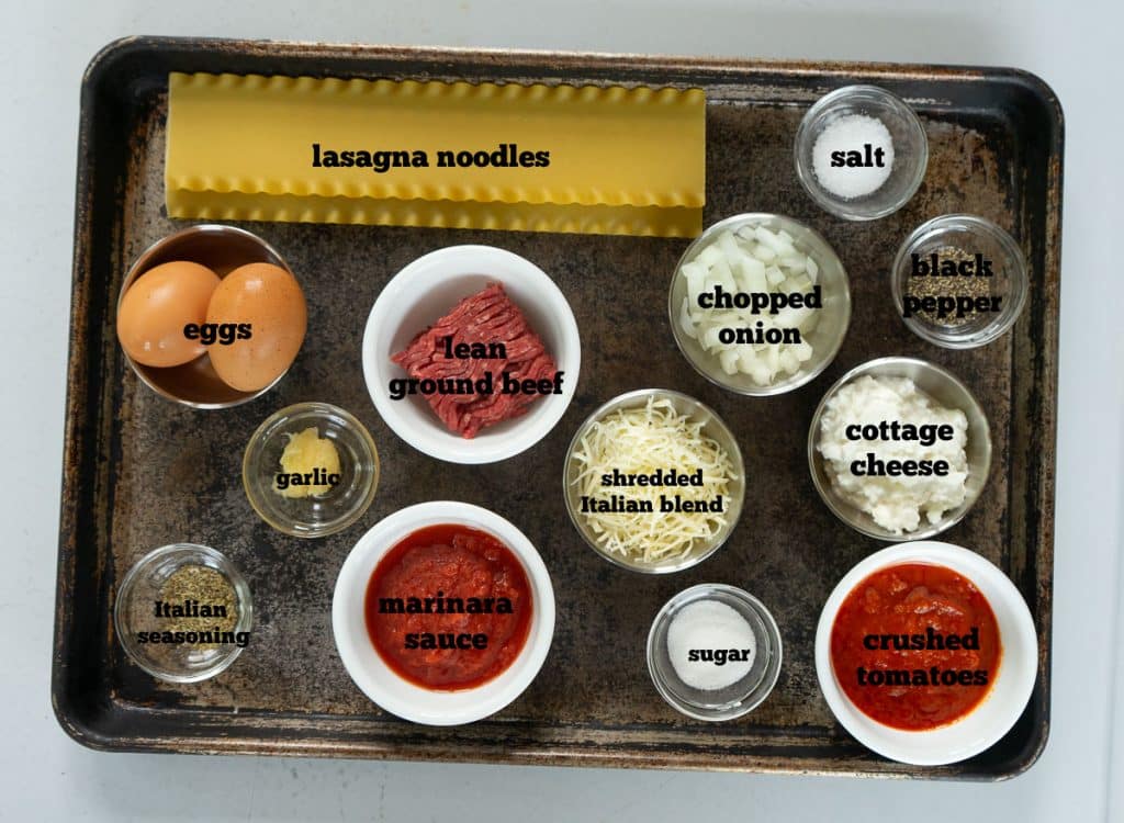 ingredients for lasagna roll ups on a baking sheet on  a gray countertop