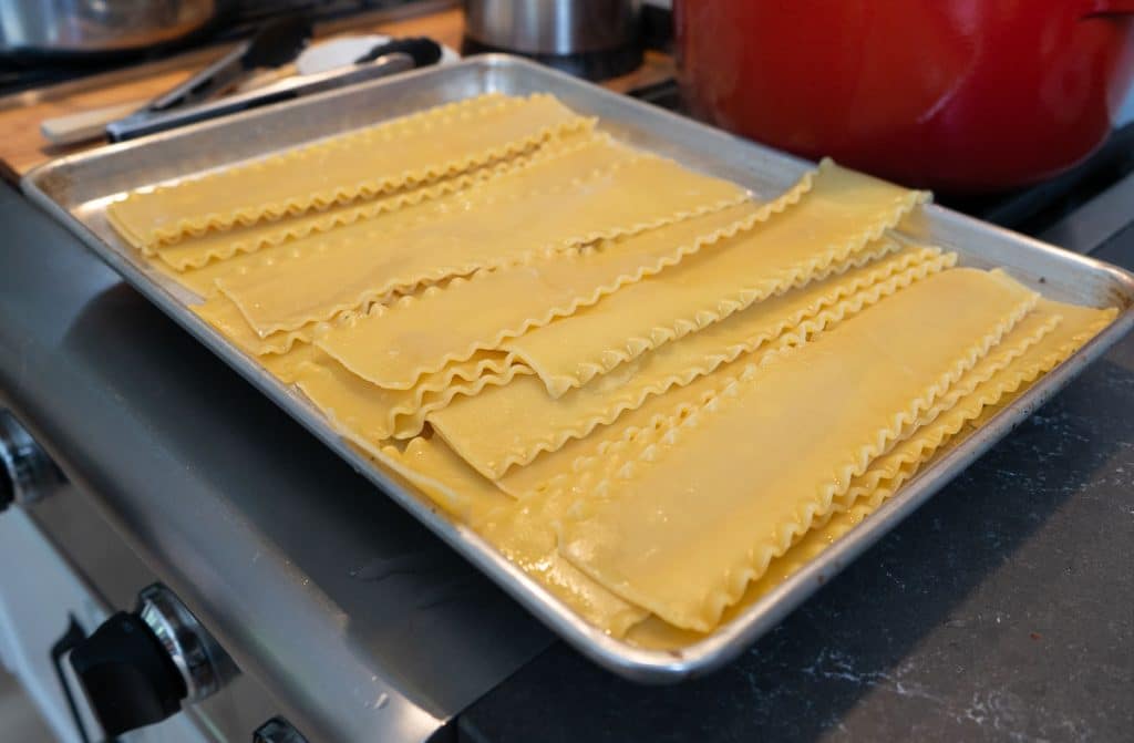 cooked lasagna noodles on a baking sheet setting on the stove top