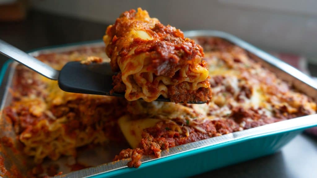 spatula scooping lasagna roll up out of the pan showing the rollup from the side 