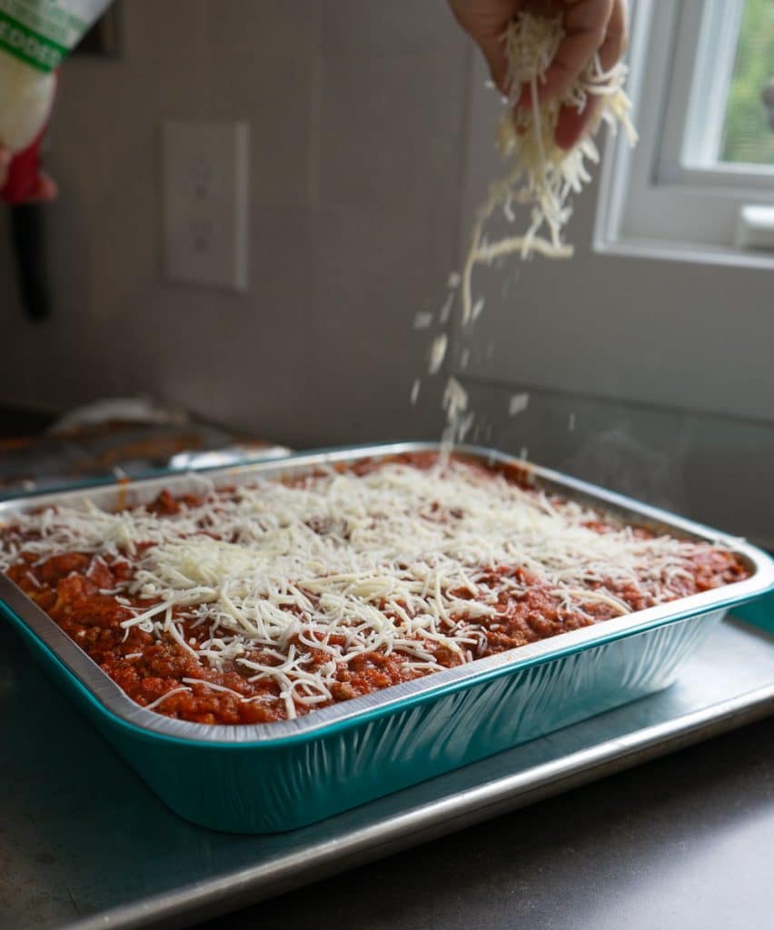 Sprinkling cheese over top of lasagna roll ups 