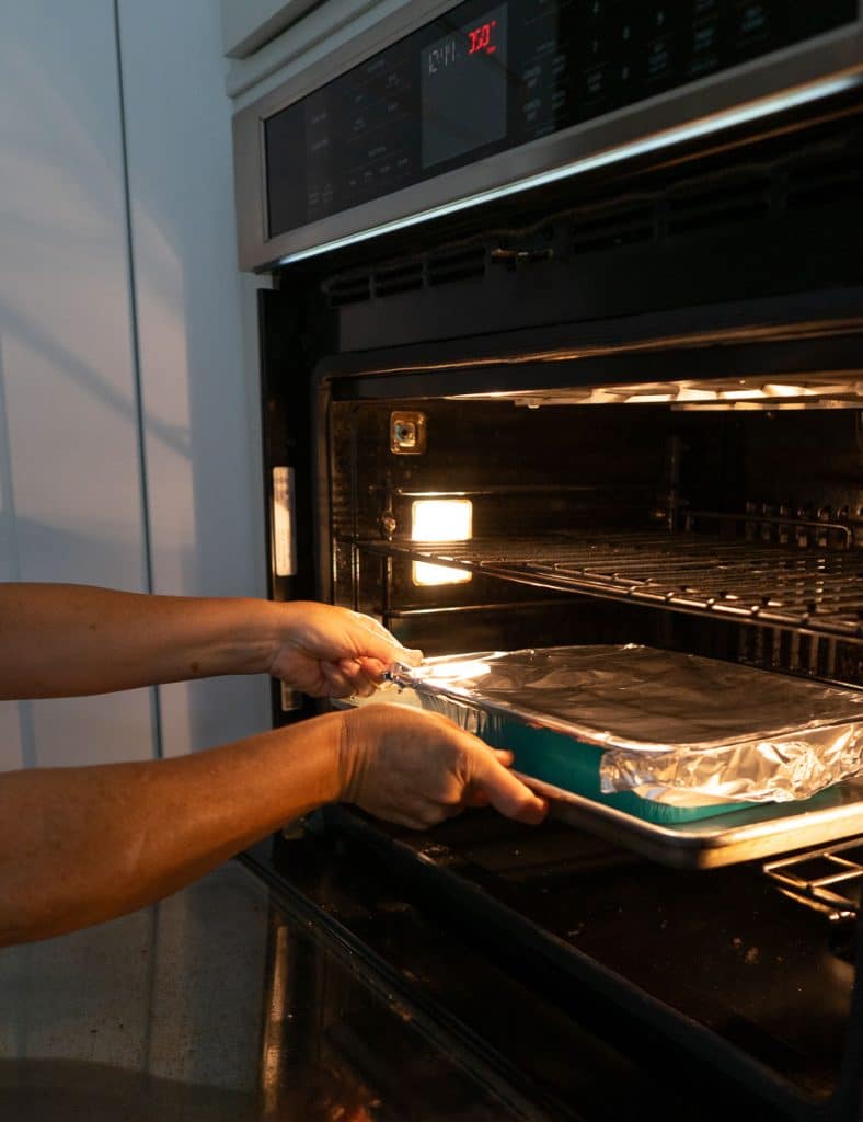 putting foil covered pan into a preheated oven