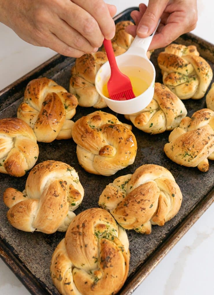brushing leftover butter over rolls after they have baked
