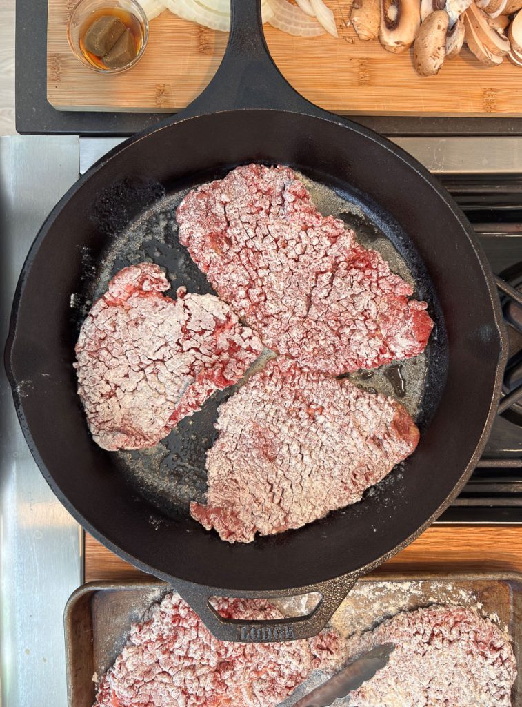 frying steaks in a cast iron skillet on the stove top