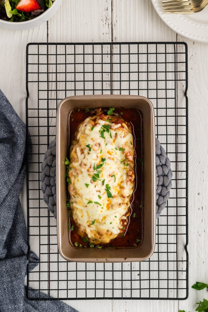 Baked meatloaf in a loaf pan on a cooling wrack