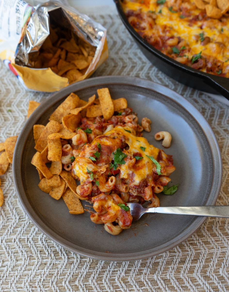 plate of one pan chili mac garnised with cilantro and topped with chili cheese fritos