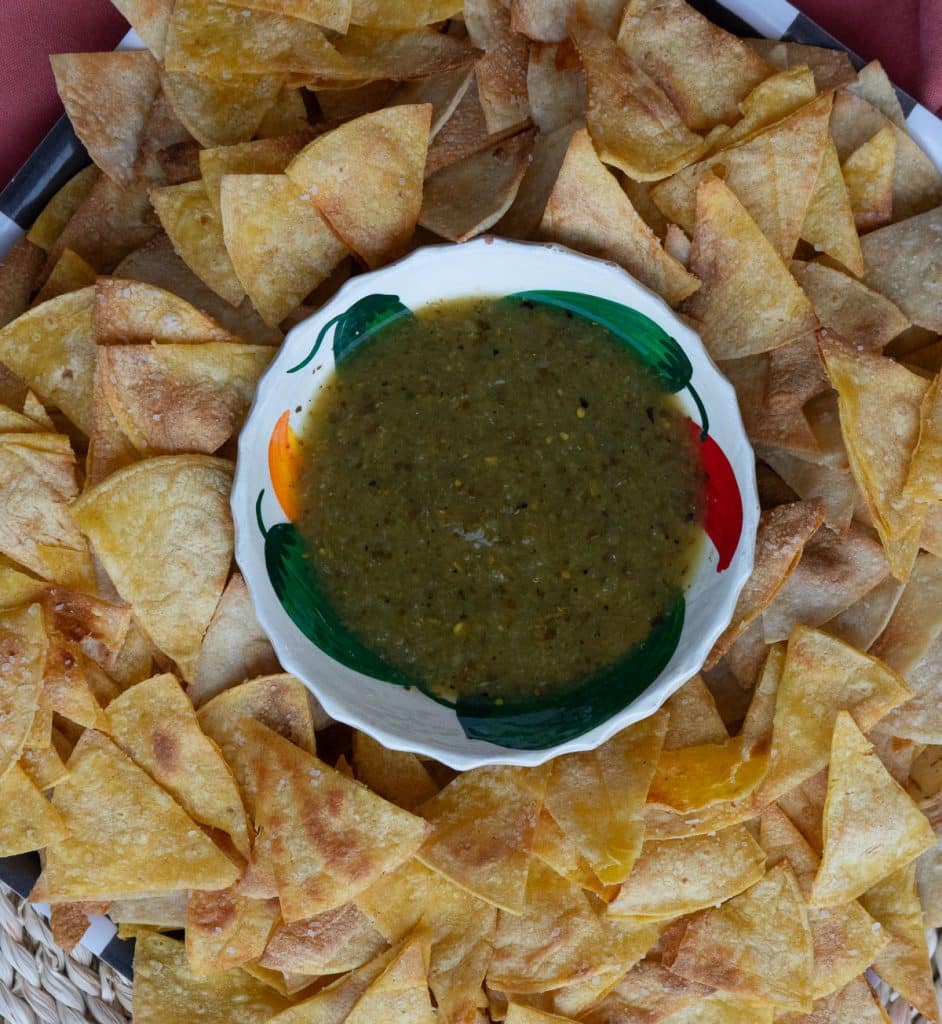 plate of homemade corn tortilla chops with a bowl of salsa verde in the middle