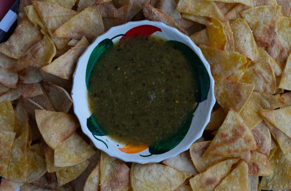 plate of homemade corn tortilla chops with a bowl of salsa verde in the middle