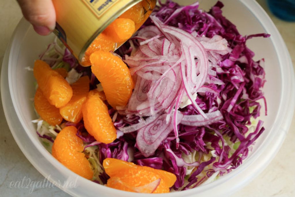 dumping can of mandarin oranges in with coleslaw ingredients
