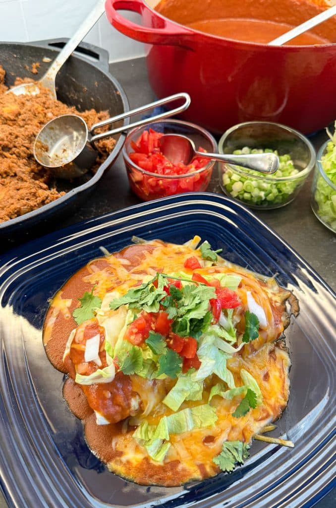 fully made wet burrito on a blue plate in from of all the wet burrito components