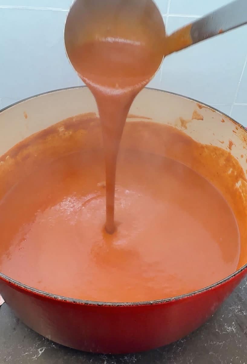 ladling wet burrito sauce over the steaming pot of sauce