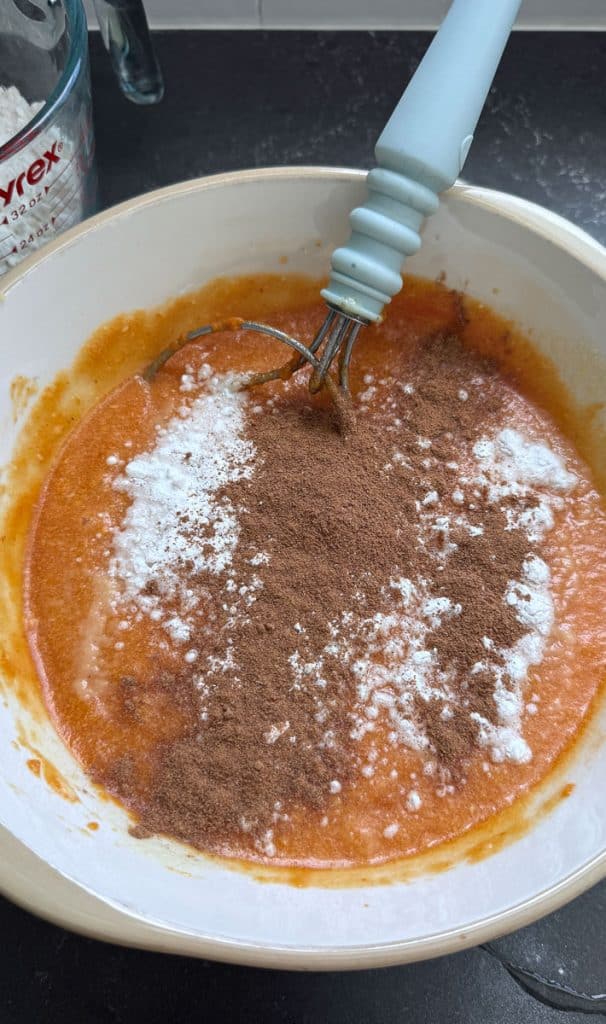 adding spices to batter of pumpkin bread