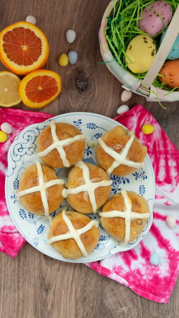 hot cross buns on a plate surrounded by easter decor 