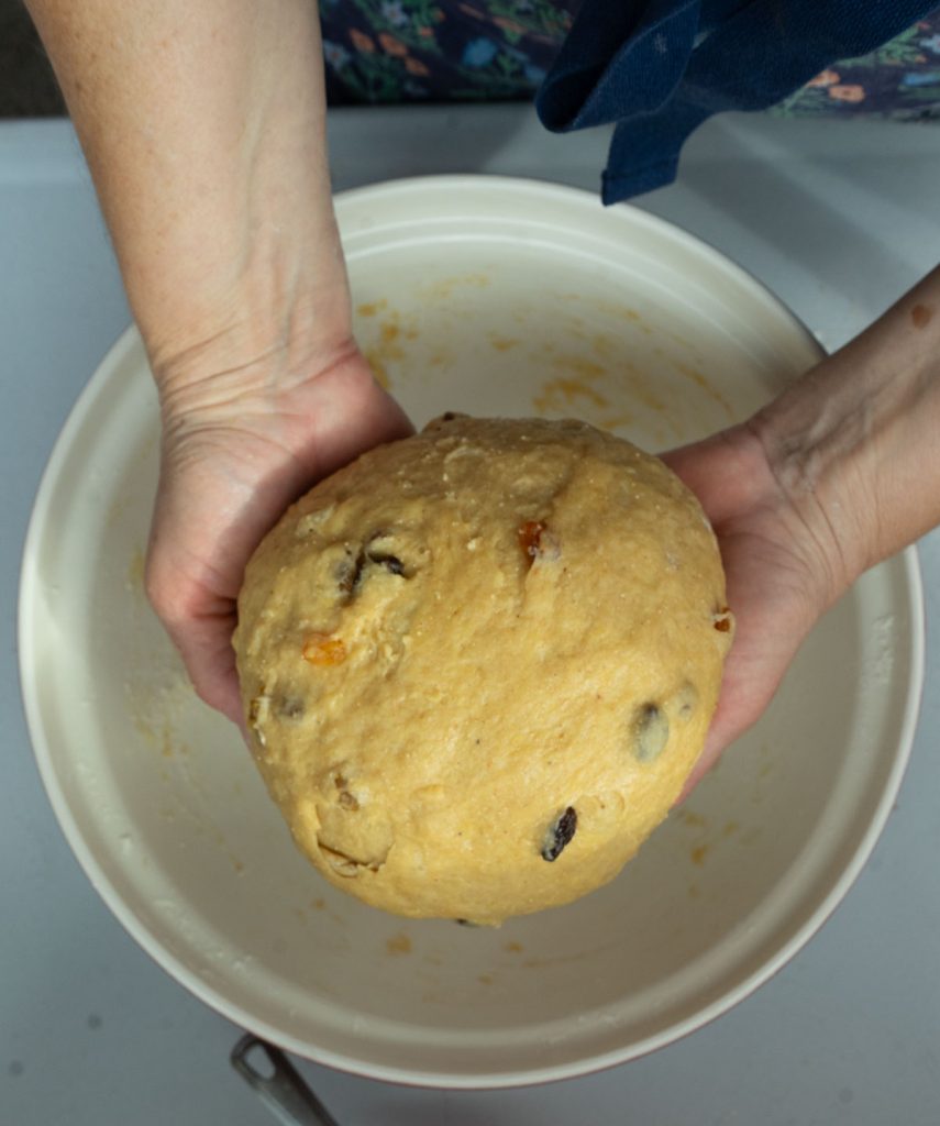 hands holding dough over bowl