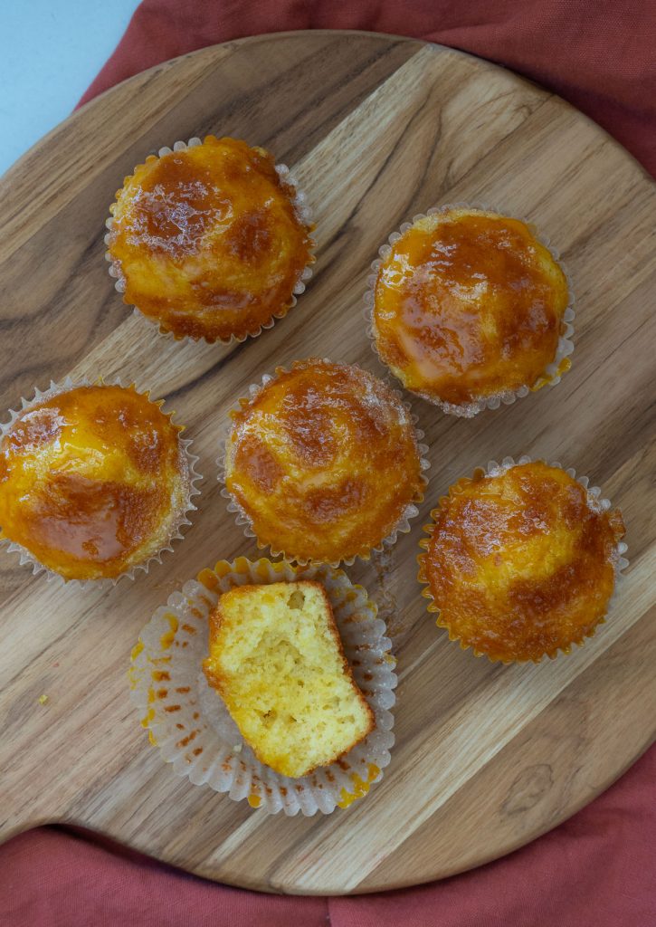 muffins on a round wood cutting board, one muffin is cut in half  laying on its side