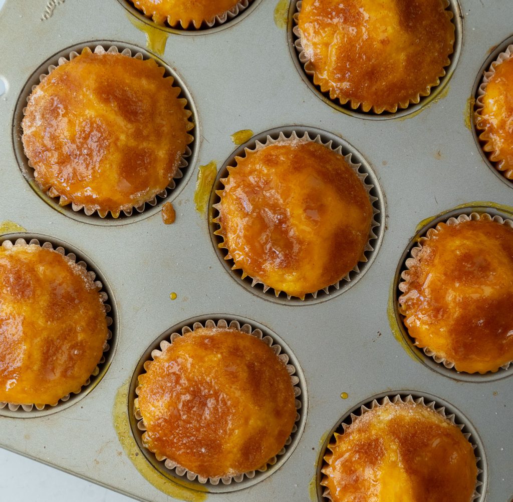 warm muffins drizzled with orange juice reduction in muffin pan