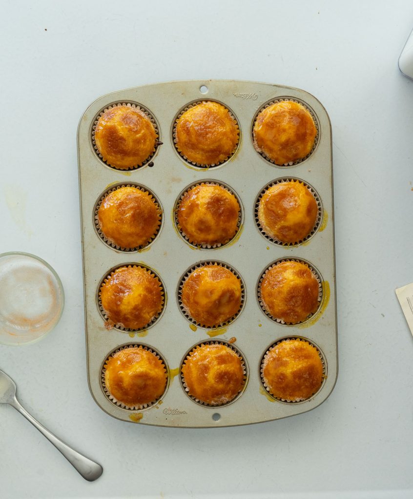 muffin tin with orange kissed muffins on a white countertop