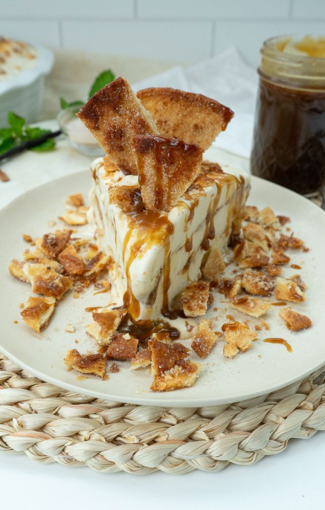 piece of churro ice cream pie with a jar of caramel sauce in the upper right corner