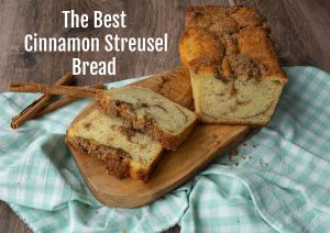 photo of cinnamon bread on a wood plank with 2 slices cut from loaf, cup of coffee off to the side