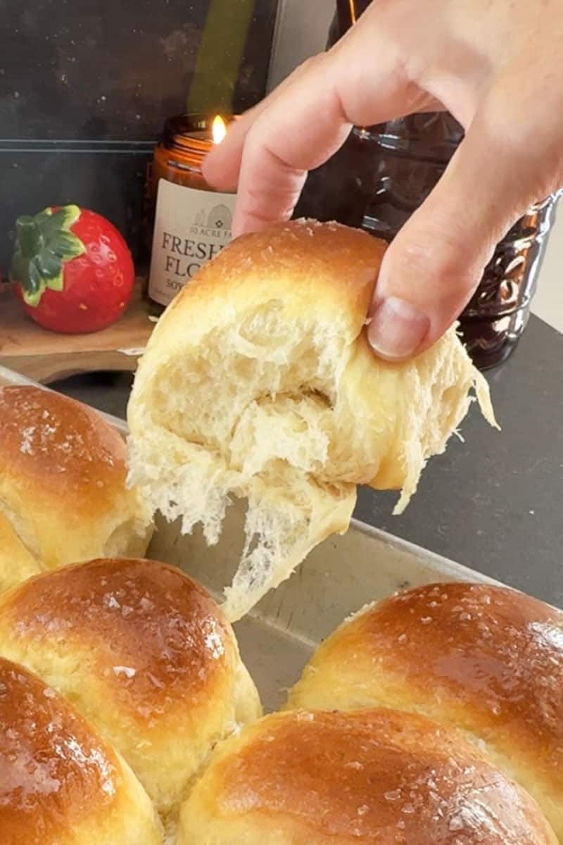 hand lifting a warm roll out of the baking pan