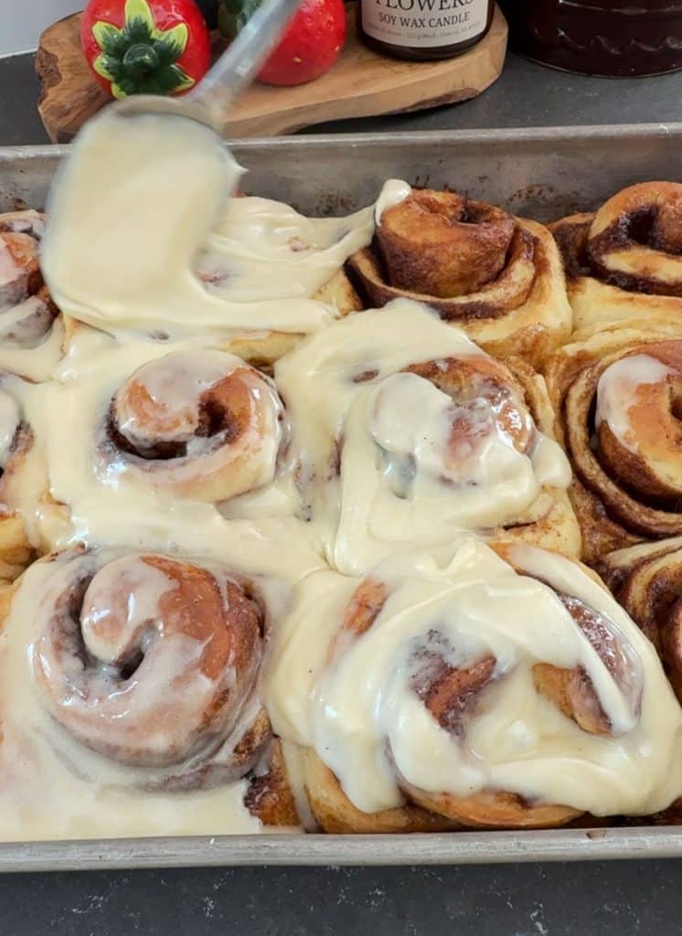 brushing glaze over cinnamon rolls