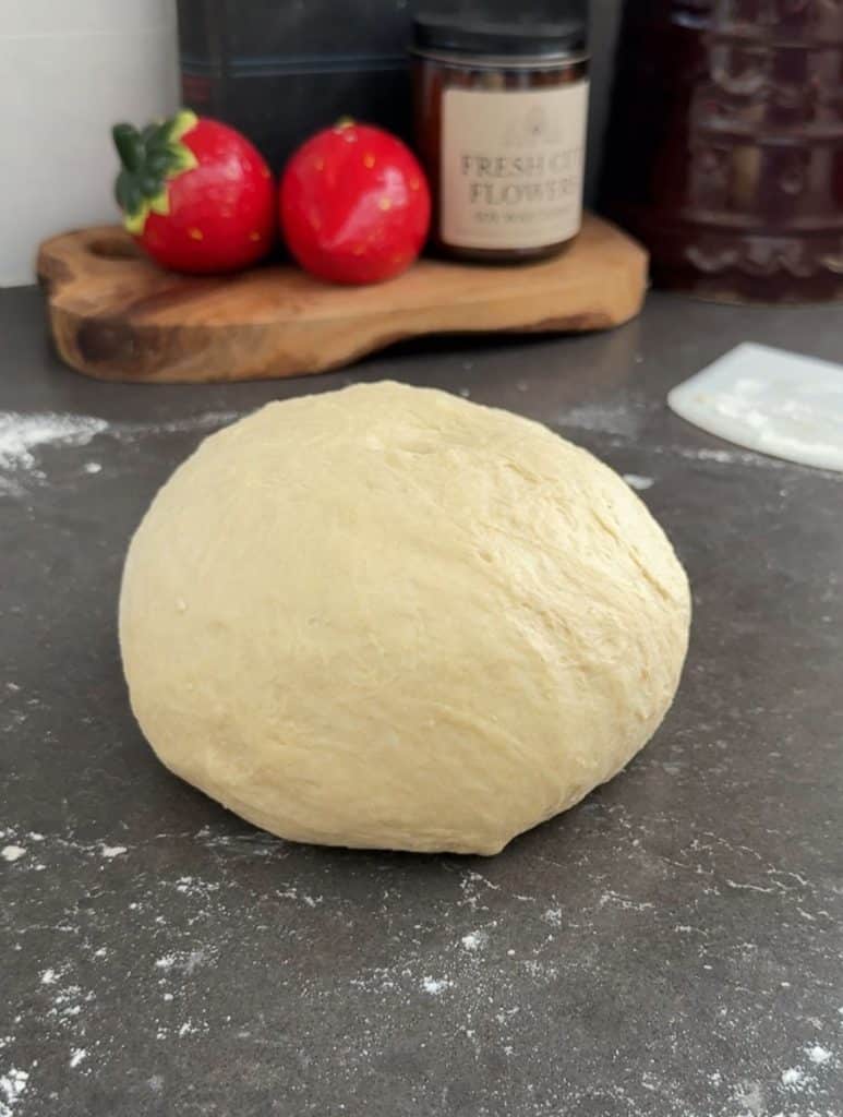 kneaded ball of dinner roll dough sitting on countertop