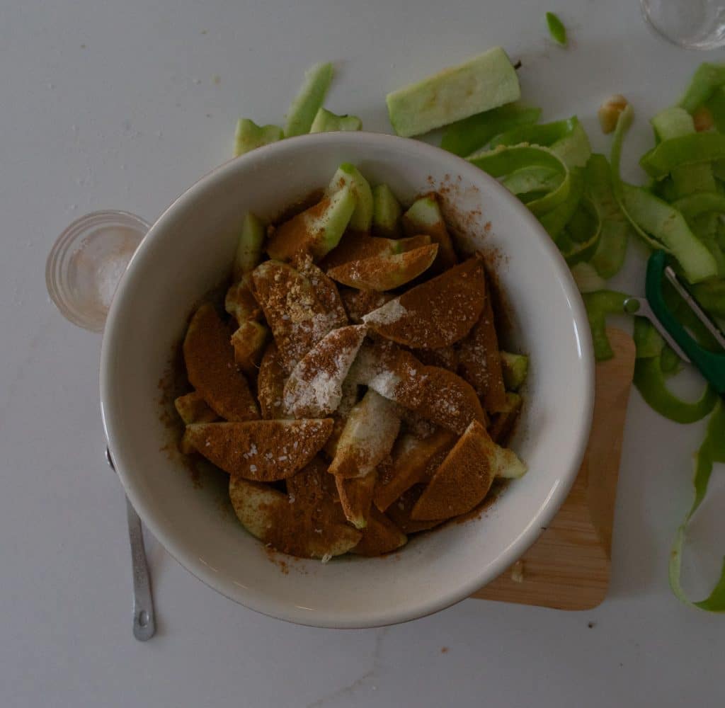 sliced apples in a bowl covered with spices