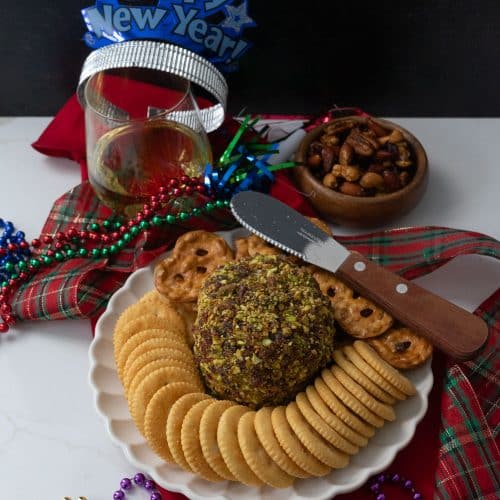 cheese ball with new years eve party favors and a glass of wine on a table