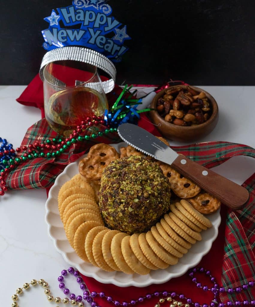 cheese ball with new years eve party favors and a glass of wine on a table