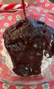 dish of vanilla ice cream with hot fudge getting poured over it