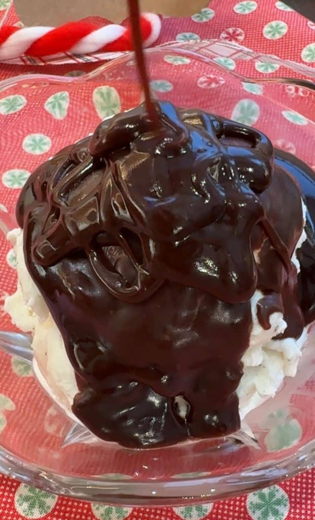 dish of vanilla ice cream with hot fudge getting poured over it