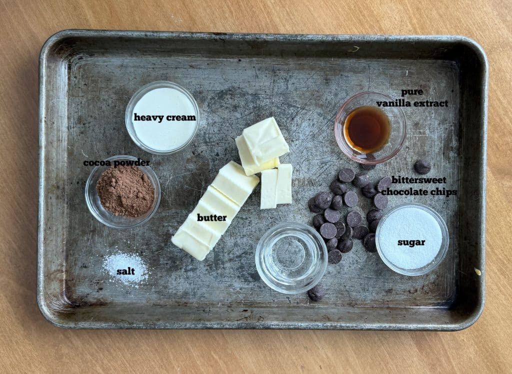 ingredients for hot fudge on a baking sheet on a wood table