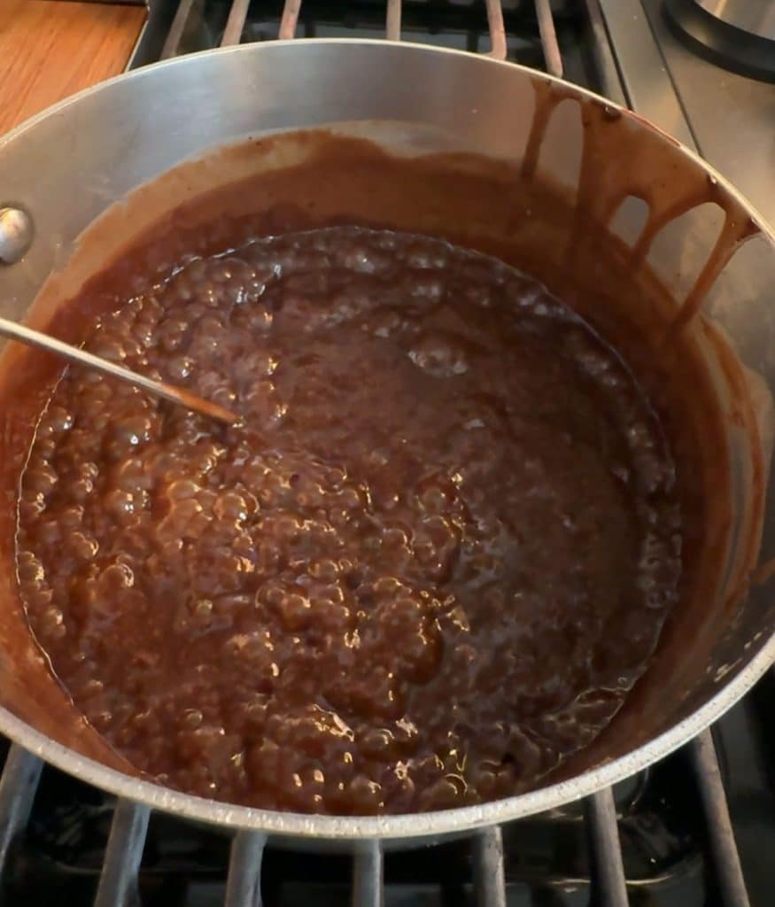 hot fudge bubbling in sauce pan, with a candy thermometer taking a reading