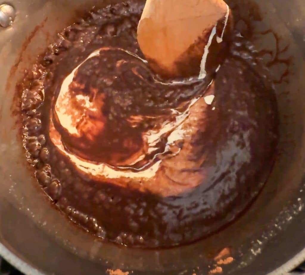 adding heaving whipping cream to hot fudge in sauce pan on stovetop