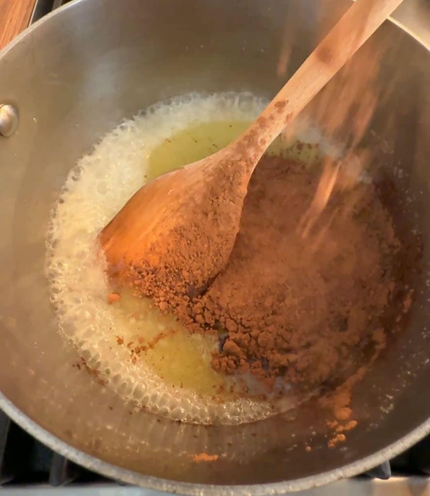 butter, sugar, cocoa powder in a sauce pan with a wooden spoon