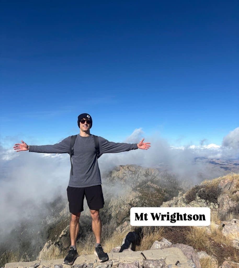 man standing arms out stretched on the top of Mount Wrightson south of Tucson Arizona