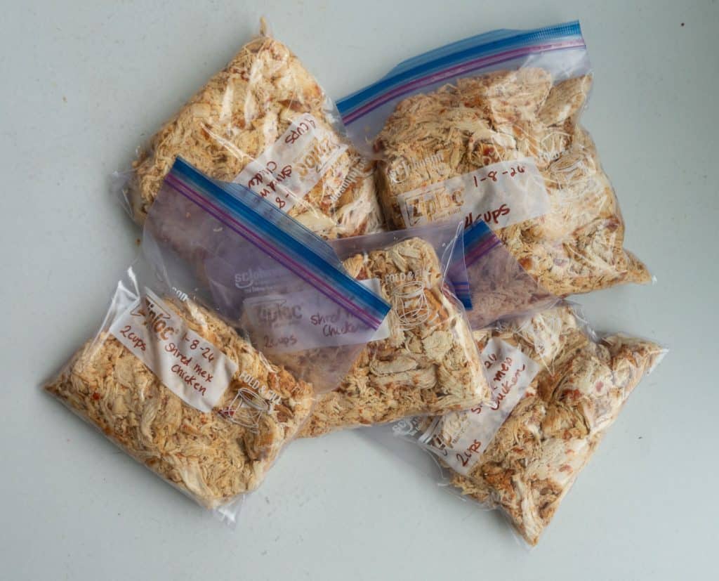 Zip-loc bags of shredded chicken on a white countertop