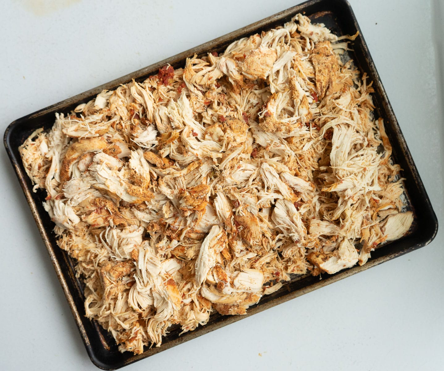 Pan of shredded mexican chicken on a white countertop