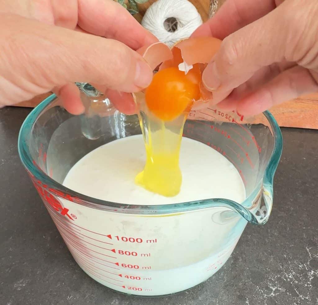 adding egg to measuring cup of buttermilk