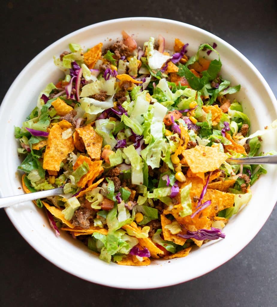 tossing salad with all the ingredients in a large bowl