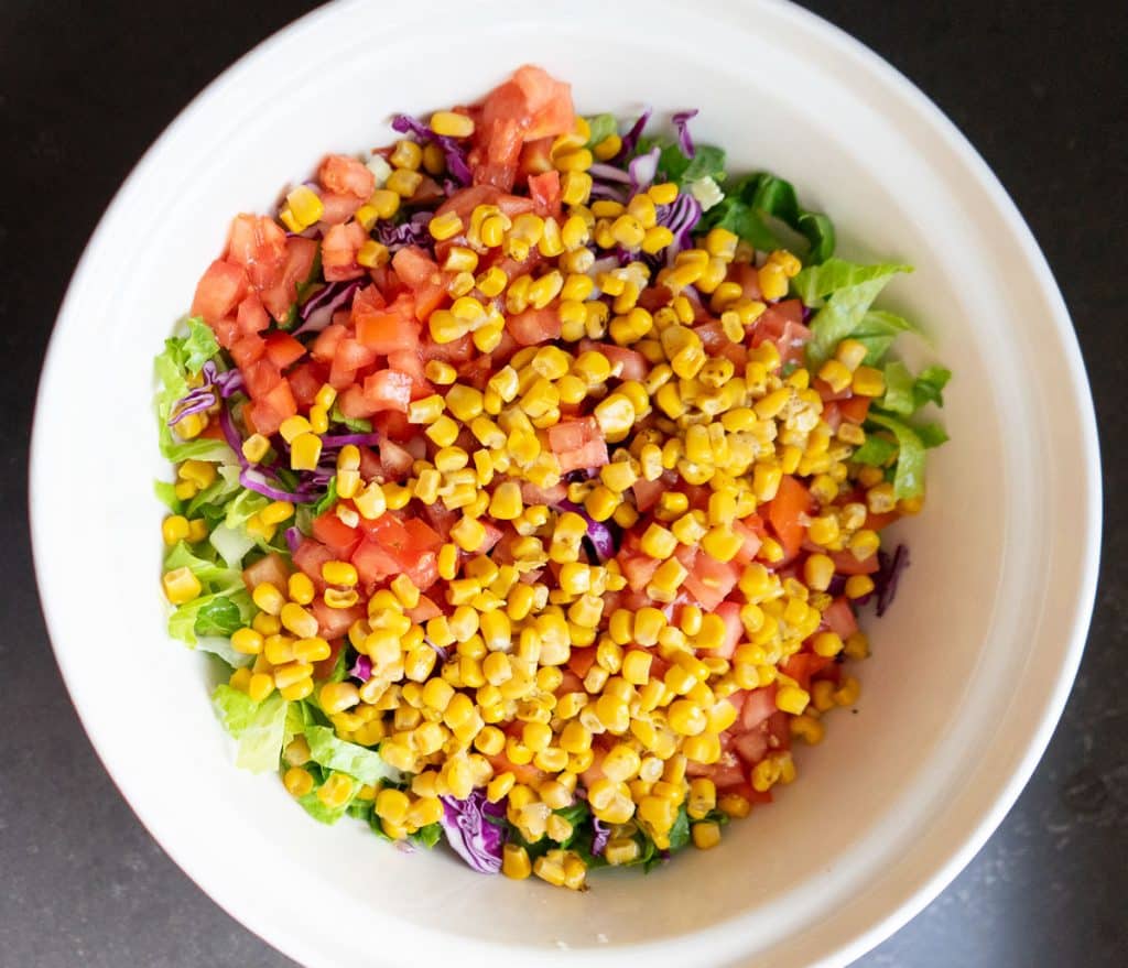 lettuce, tomato, corn in a large bowl