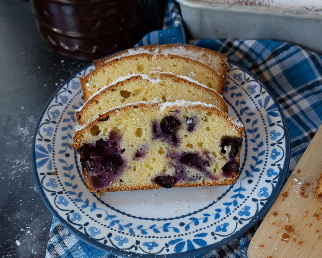 photo of slices of pound cake with blueberries on a plate with a blue rim