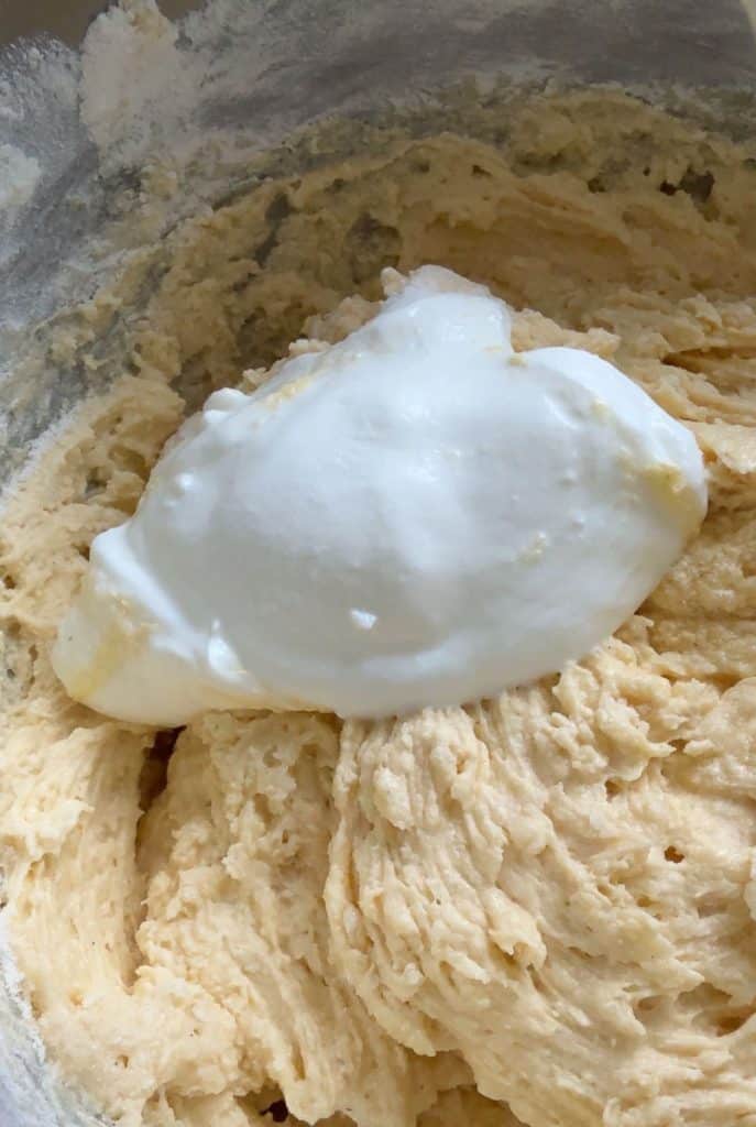 adding sour cream to butter sugar mixture in mixing bowl