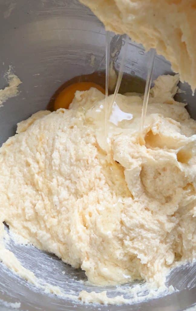 adding eggs to butter sugar mixture in mixing bowl