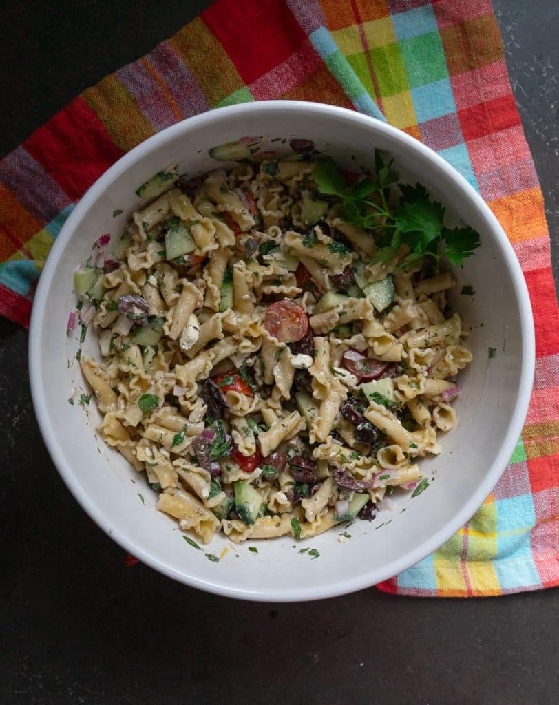 bowl of greek pasta salad on a multi colored towel