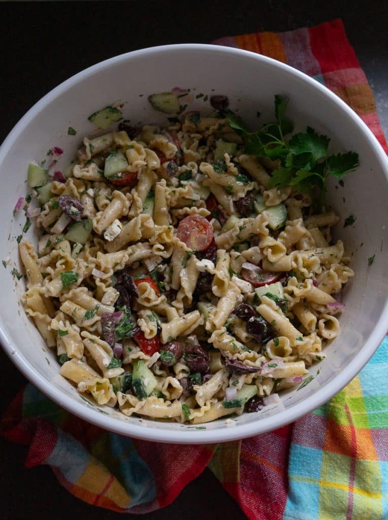 bowl of greek pasta salad on a multi colored towel