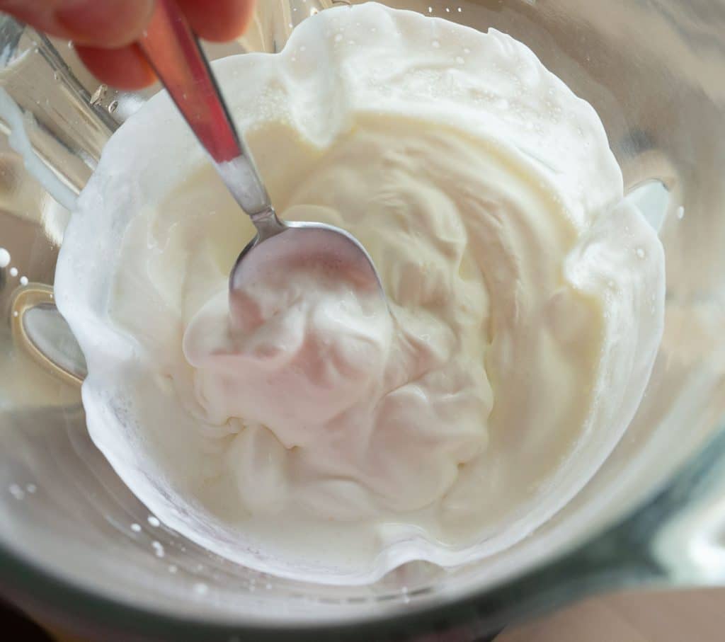 whipped cream in blender with a spoon showing the consistency