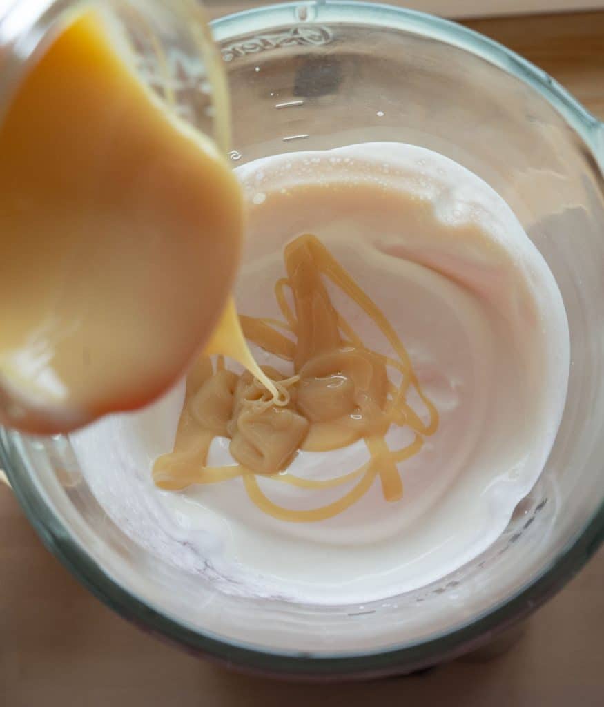 adding sweetened condensed milk to the whipped cream in the blender