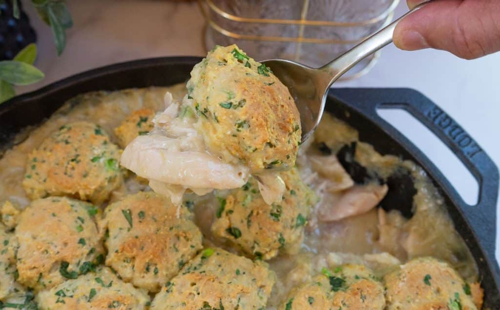 a spoon scooping up southwest chicken and dumplings out of cast iron skillet