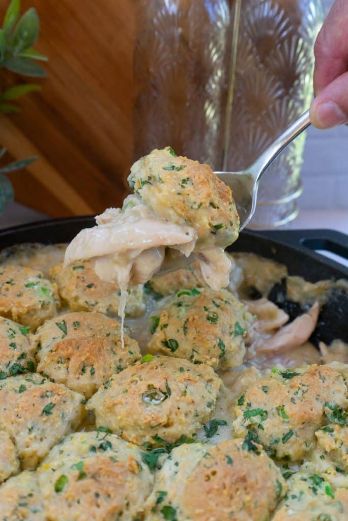 a spoon scooping up southwest chicken and dumplings out of cast iron skillet